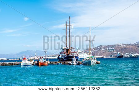 Icredible view of sailing yachts and boats moored to the stone pier on the tranquiose sea bay and mountanious landscape of greece island