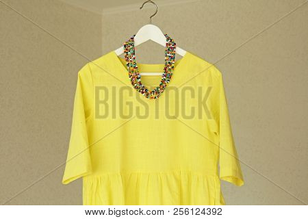 Bright Beads Of Murano Glass Hang On The Background Of A Yellow Summer Dress. Summer Jewelry, Summer