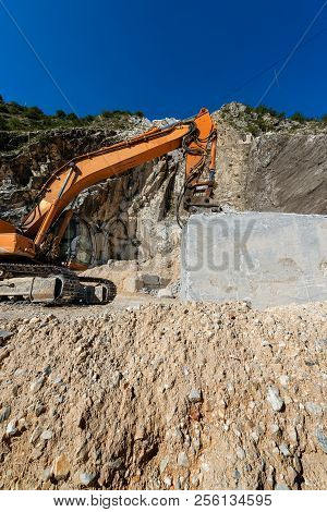 Orange Tracker Excavator With The Jackhammer In A Marble Quarry (carrara White Marble) In The Apuan 