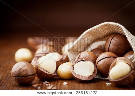 Natural Macadamia Nuts In Canvas Bag On Wooden Table.