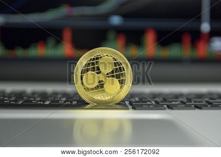 Golden Ripple Coin On A Black Keyboard Of Silver Laptop And Diagram Chart Graph On A Screen As A Bac