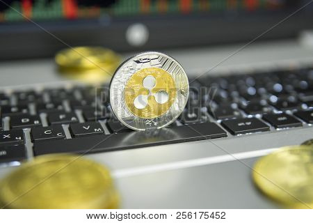 Golden And Silver Ripple Coin With Gold Coins Lying Around On A Black Keyboard Of Silver Laptop And 
