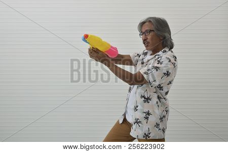 Happy Senior Traveler Asian Man Wearing Glasses, Summer Shirt And Brown Shorts Holding Colorful Wate