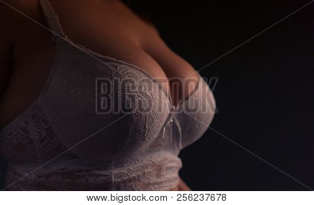 Big Beautiful Breasts In A White Bra On A Black Background Close-up.