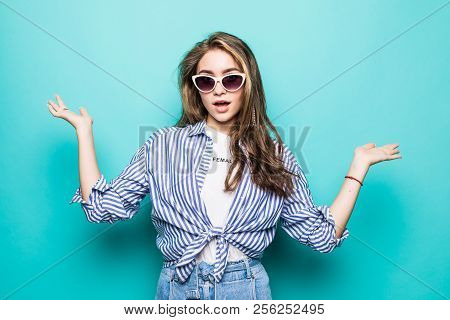 Pretty Smiling Woman In Blue Shirt Isolated On Blue Background Asking You To Make A Choice Between T