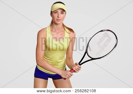 Indoor Shot Of Active Beautiful Female Tennis Player Stands In Ready Posture, Plays Tennis, Ready To