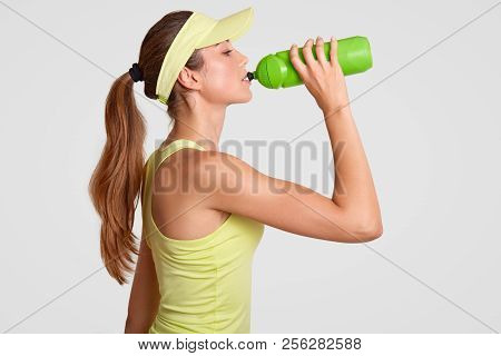 Sideways Shot Of Exhausted Tennis Player Drinks Water As Feels Thirrsty After Active Game, Has Fit B