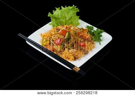 Mi Xao Stir-fried Noodles Asian Meals On Triangle Plate Isolated On Black. Served With Chopsticks.