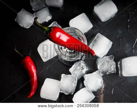 A Shot Of Vodka, An Alcoholic Beverage, Next To Ice, Fire, Ice, Red Chili Pepper. The Concept Of Alc