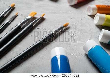 Painting Brusches, White Paper And Watercolors On Gray Concrete Background. Flat Lay, Top View