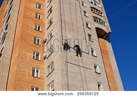 Industrial Climbing. Workers Hang The Advertising On A Building. Work At Height