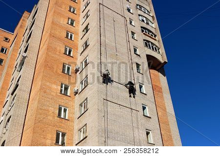 Industrial climbing. Workers hang the advertising on a building. Work at height