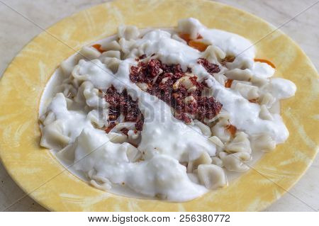 Traditional Taste Turkish Ravioli With Yellow Banded Plate With Tomato Sauce And Yogurt