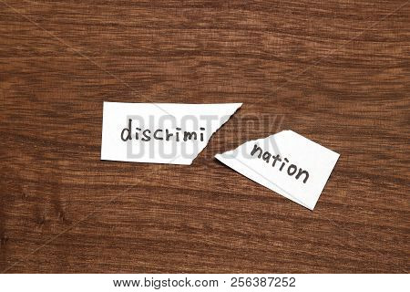 The Paper Written As Discrimination Is Torn On Wood. Concept Of Abolition Of Discrimination.