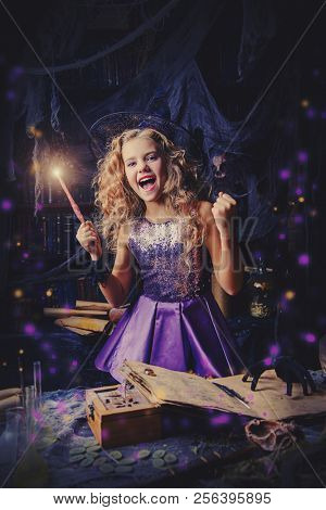 Beautiful charming little witch conjures in her lair. Halloween. 