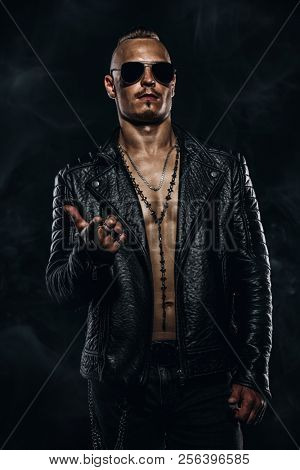 Dark portrait of a serious gangster man with  gun wearing black leather jacket.