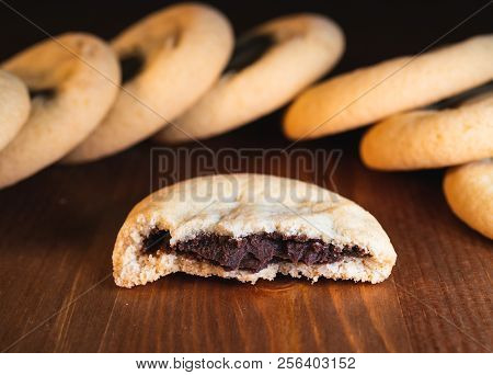 Chocolate Filled Cookies Cut In Half With Chocolate Cream And Cookies In The Back On Wooden Backgrou