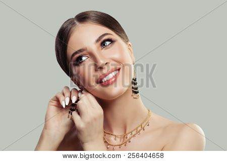 Beautiful Smiling Woman Puting On Gold Fashion Jewelry Earrings With Black Gemstones. Beauty And Acc