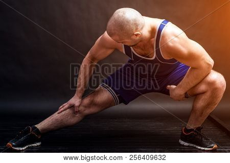 A Young Athletic Man In Blue Wrestling Tricky And Blue Shorts Makes A Stretch On A Black Isolated Ba