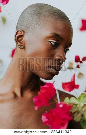 Skinhead woman surrounded by red flowers