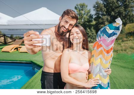 Nice Picture Of Bearded Guy And Well-built Girl Standing And Posing On Camera. They Take Selfie On P