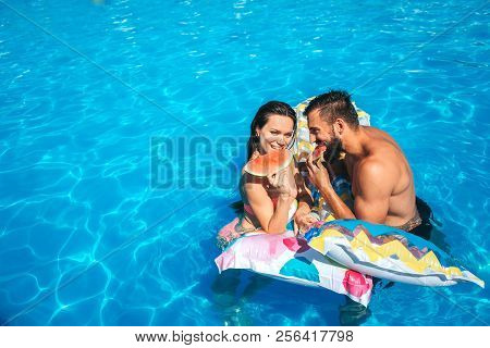 Nice Picture Of Couple Leaning To Air Mattress And Eating Watermelon. They Look At Each Other. Coupl