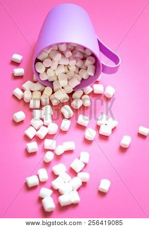 White Marshmallow Poured From A Purple Cup On A Pink Background. Close-up