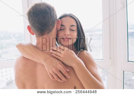 Calm And Peacul Young Woman Stands With Guy And Embrace Him. She Keeps Her Eyes Closed And Smile. Gi
