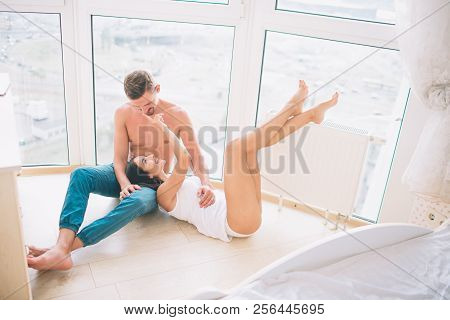 Nice Man Sits On Floor And Looks At Girl. She Lies On His Knees And Touches Face. Young Woman Keeps 