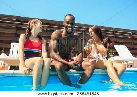 Happy Smiling African Man And Women As Friends Playing And Relaxing In A Swimming Pool During Summer