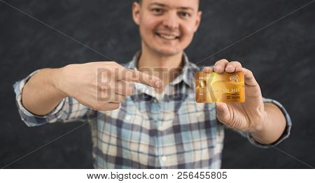 Cheerful Cardholder Looking At Camera. Young Smiling Man Holding Credit Card And Point At It, Bank C