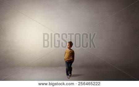 Little waggish kid staying alone in a big empty room with his plush