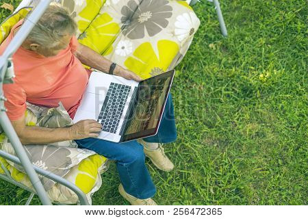 Top View Of Eldery Man Sitting And Relaxing On A Summer Holiday Rasort Using Laptop On Grass On Couc