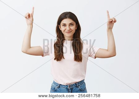 Cute And Friendly Aduly Woman With Brown Hair In Pink Stylish T-shirt And Jeans Raising Index Finger