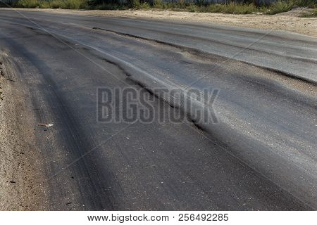 Damaged Road, Damaged Chopped Asphalt With Potholes And Spot. Very Bad Asphalt Road With Large Trenc