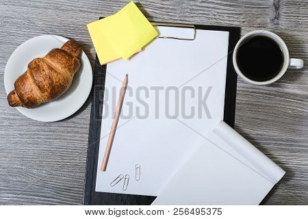 Office Accessorise On Wooden Gray Table: Clipboard, Cup Of Coffee, Fresh Croissant