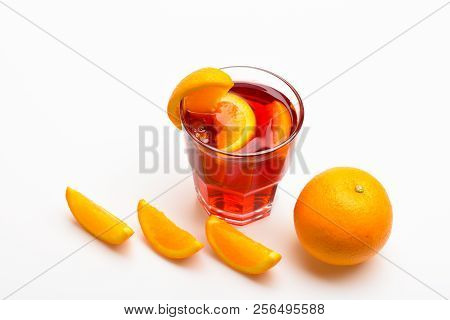 Glass With Orange Drink Near Juicy Orange Fruit On White Background, Close Up. Cocktail Or Beverage 