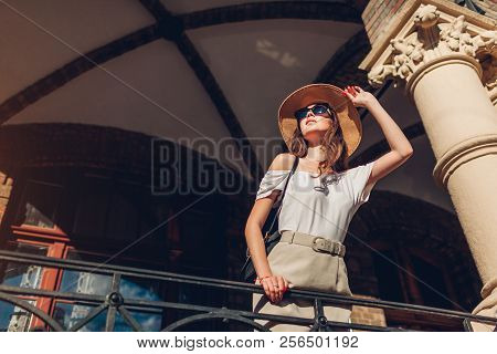 Outdoor Portrait Of Young Tourist Woman Enjoying Sightseeing In Lviv. Girl Looking At Ancient Atchit