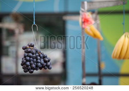 Black Grapes Hanging In The Air On A Hook In A Market Of Serbia. Black Grapes Are A Typical Fruit Ha