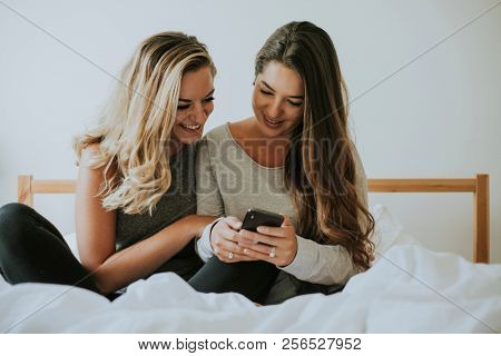 Girls playing with a phone in bed