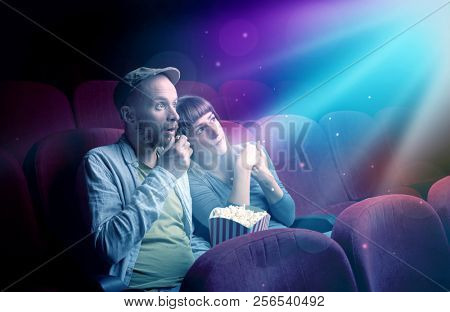 Teenager couple cuddling and watching the climax part of the movie