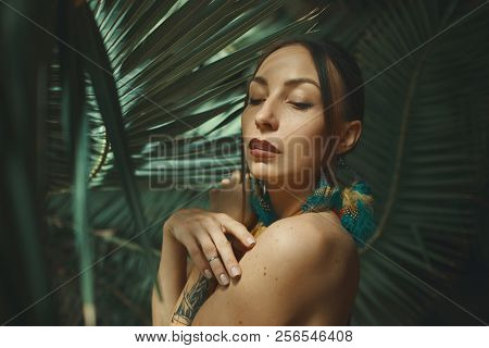 Beautiful Young Woman Posing On A Background Of Exotic Palm Leav