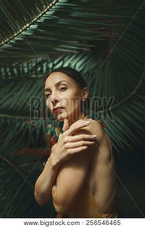 Beautiful Young Woman Posing On A Background Of Exotic Palm Leav
