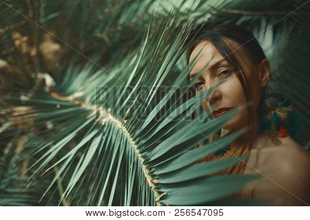 Beautiful Young Woman Posing On A Background Of Exotic Palm Leav
