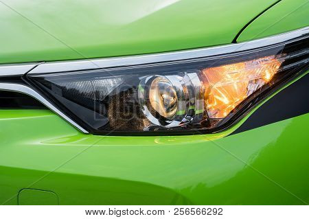 Front Headlight On A Modern Green Car. Low Beam And Turn Signal Or Blinker Lit.