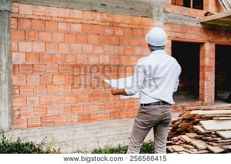 Construction Engineer With Plans, Working On Building Construction Site. Brick Walls, Infrastructure