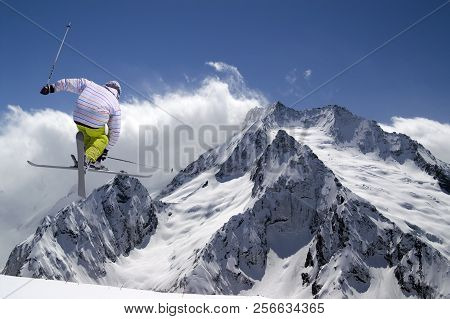 Freestyle Ski Jumper With Crossed Skis In High Snowy Mountains At Sun Winter Day