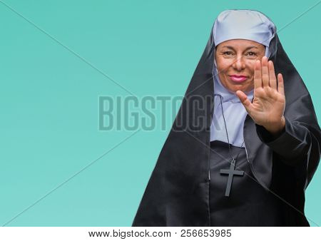Middle age senior christian catholic nun woman over isolated background doing stop sing with palm of the hand. Warning expression with negative and serious gesture on the face.