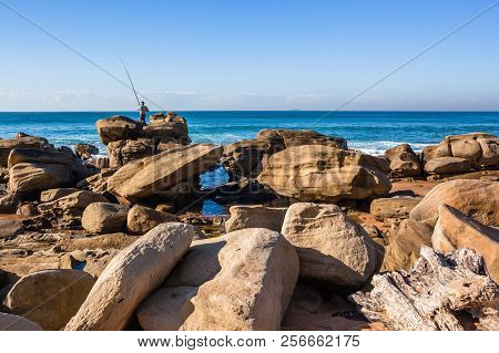 Beach Ocean Fisherman Fishing On Large Rock Boulders Towards Ocean Horizon Holiday Lifestyle  Coastl
