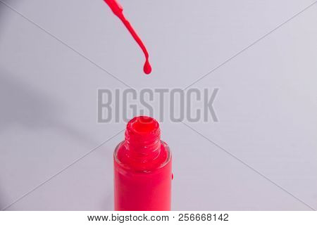 An Open Can Of Red Lacquer And A Brush With A Drop Of Lacquer On It